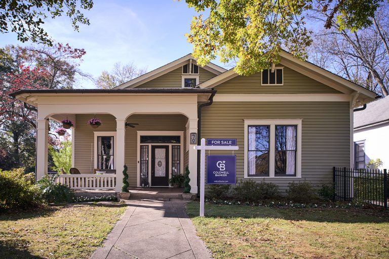 Single‑family home with a front porch and a Coldwell Banker for‑sale sign in the front yard on a sunny day.