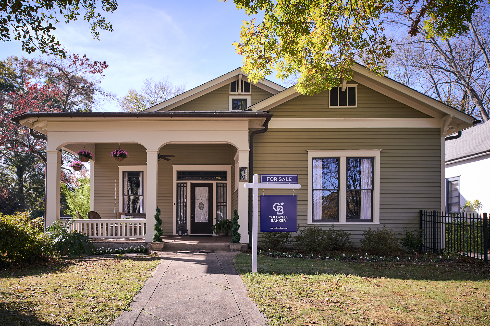 Single‑family home with a front porch and a Coldwell Banker for‑sale sign in the front yard on a sunny day.